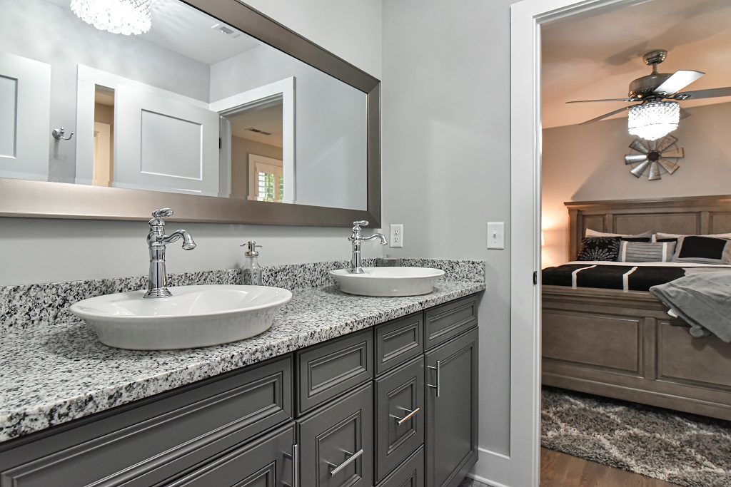 Double vanity with vessel sinks, a granite counter and a wide framed mirror