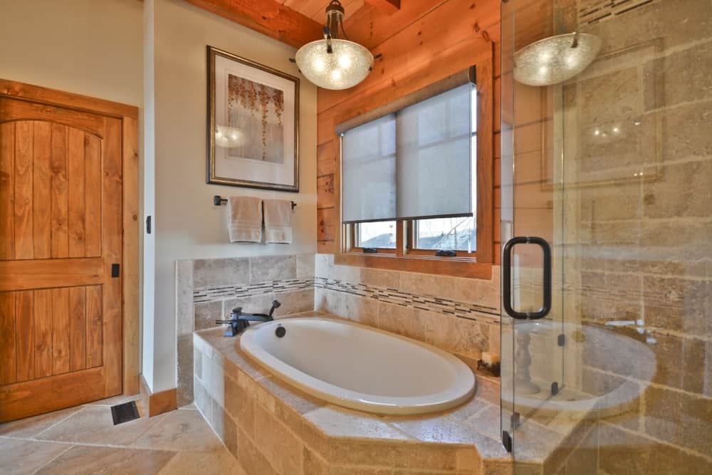 Primary bath with a tiled corner soaking tub, a glass shower and a knotty wood door