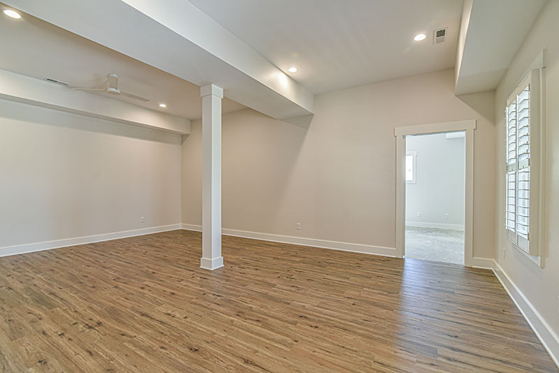 Finished lower-level room with a support column, wood floors and natural light