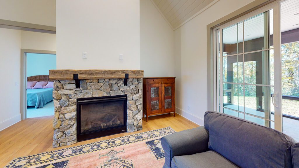 Living room with a stone fireplace and a view through to the bedroom beyond