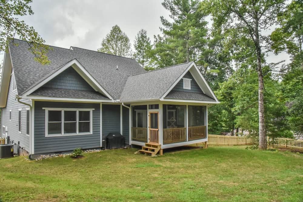 Front of the home with a screened porch, dormers and a level lawn