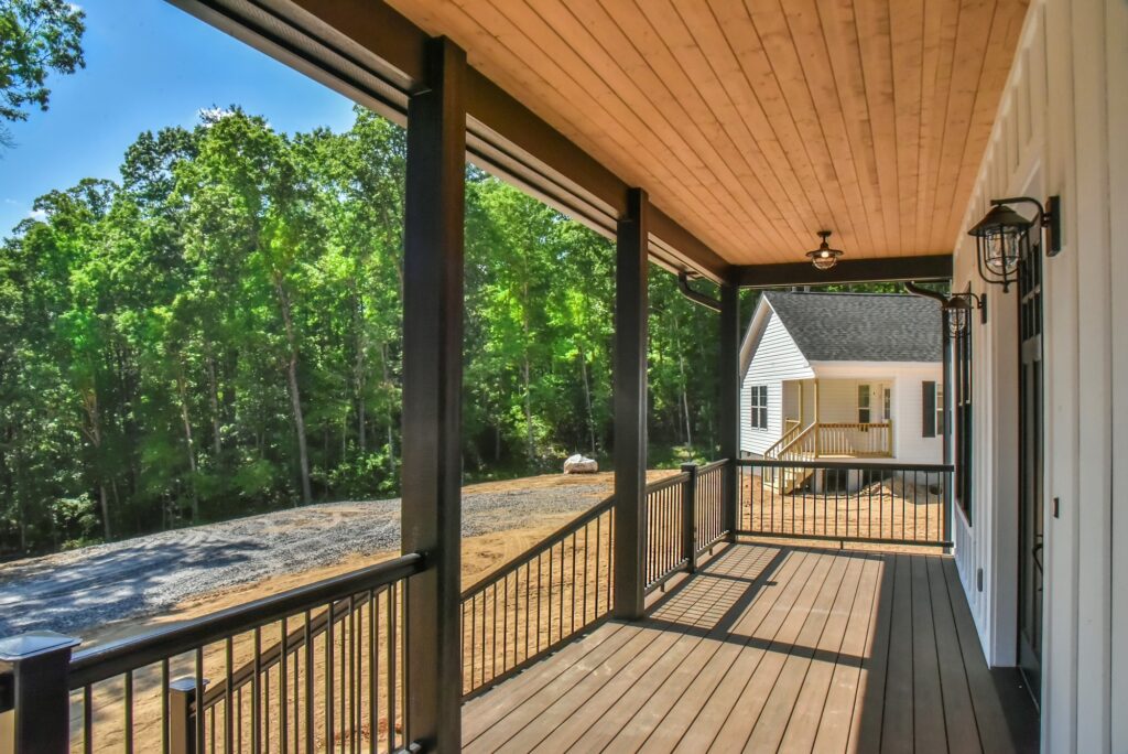Screened porch with a stained wood ceiling, black railing and woodland views