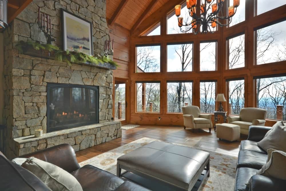 Great room with a floor-to-ceiling stone fireplace, a wall of windows and leather seating