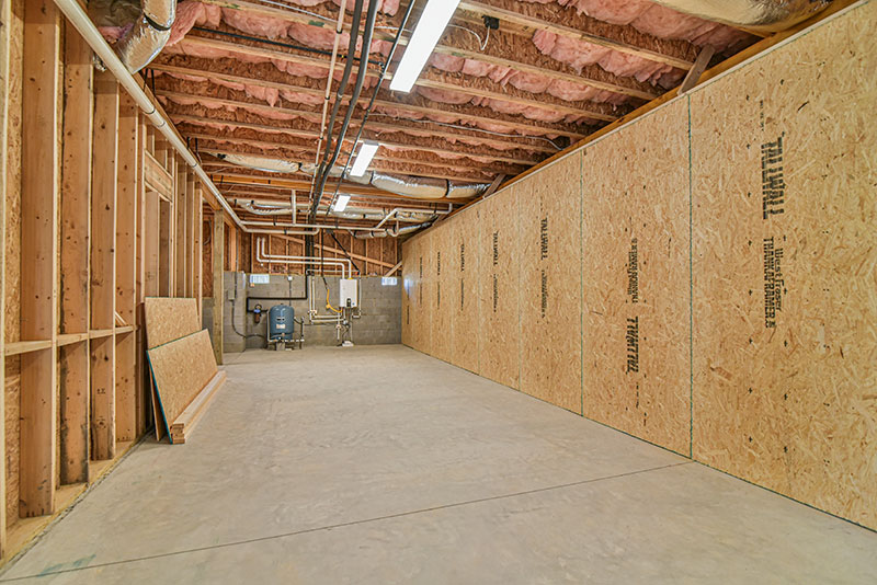 Unfinished storage area with exposed framing and a concrete floor
