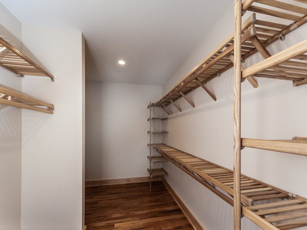 Walk-in closet with open wood shelving and hanging rods