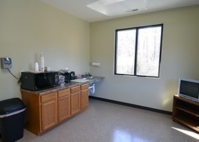 Break-room kitchen with wood cabinets, counter and a window
