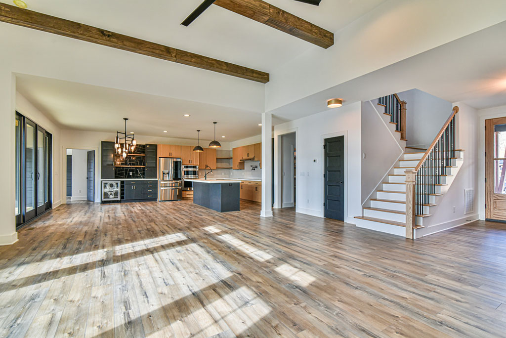 Great room with exposed beams looking toward the kitchen and staircase