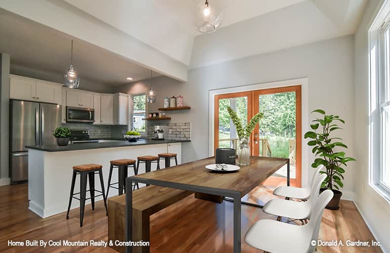 Kitchen and dining area with white cabinets, an island with bar stools and french doors