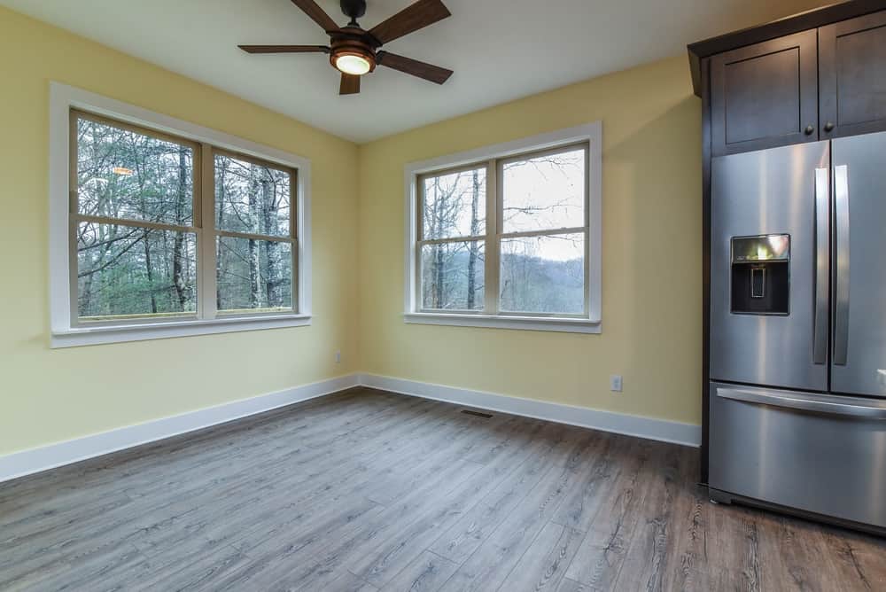 Kitchen corner with a stainless refrigerator, windows to the woods and wood-look flooring