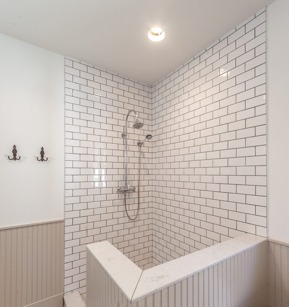 Walk-in shower with white subway tile and a built-in bench