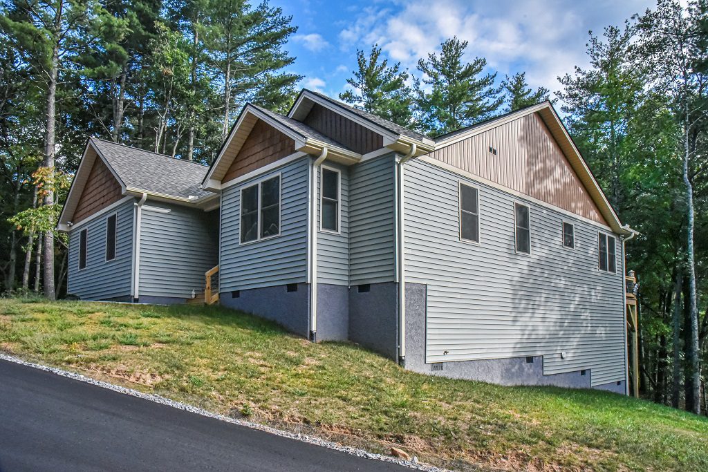 Side view of the gray ranch home with a walkout lower level and paved driveway