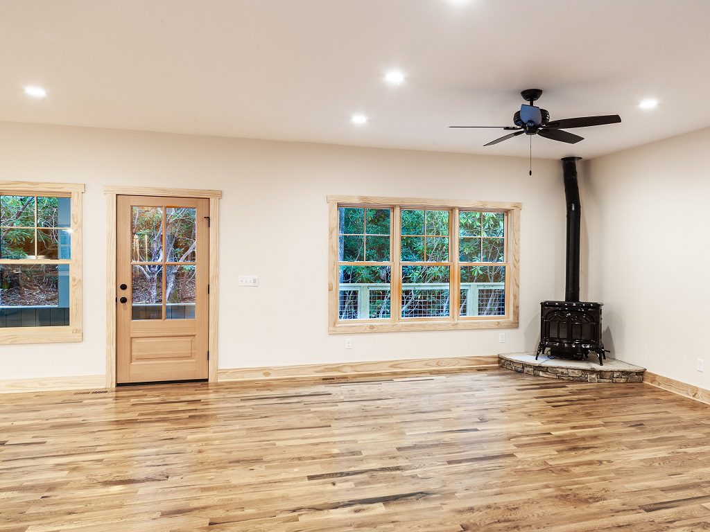 Open living area with hickory floors, a wood stove and doors to the covered porch