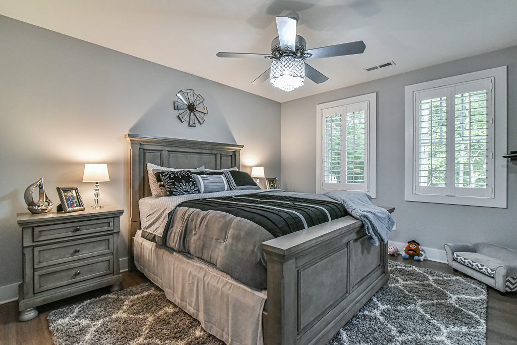 Bedroom with an upholstered bed, ceiling fan and plantation shutters