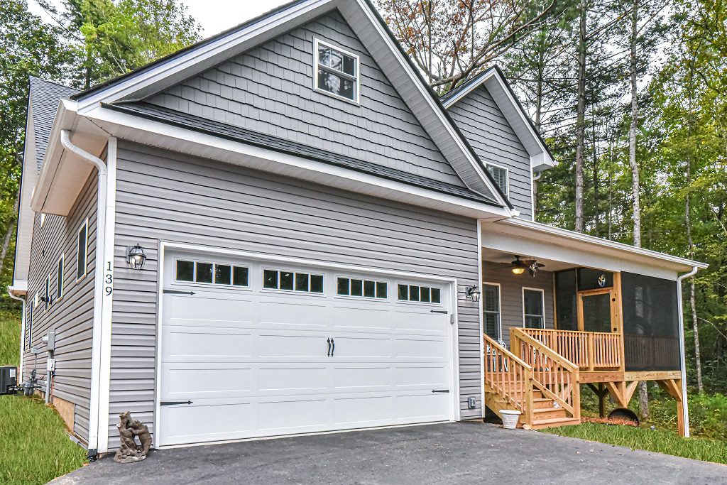 Side view of the gray home with an established lawn, garage and covered porch