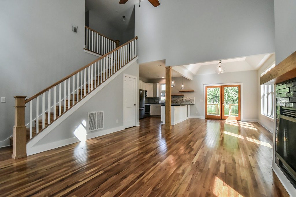 Entry and stairway looking into the open living area and kitchen with hardwood floors