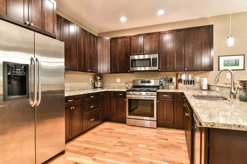 Kitchen with dark cabinets, granite counters, stainless appliances and hickory floors