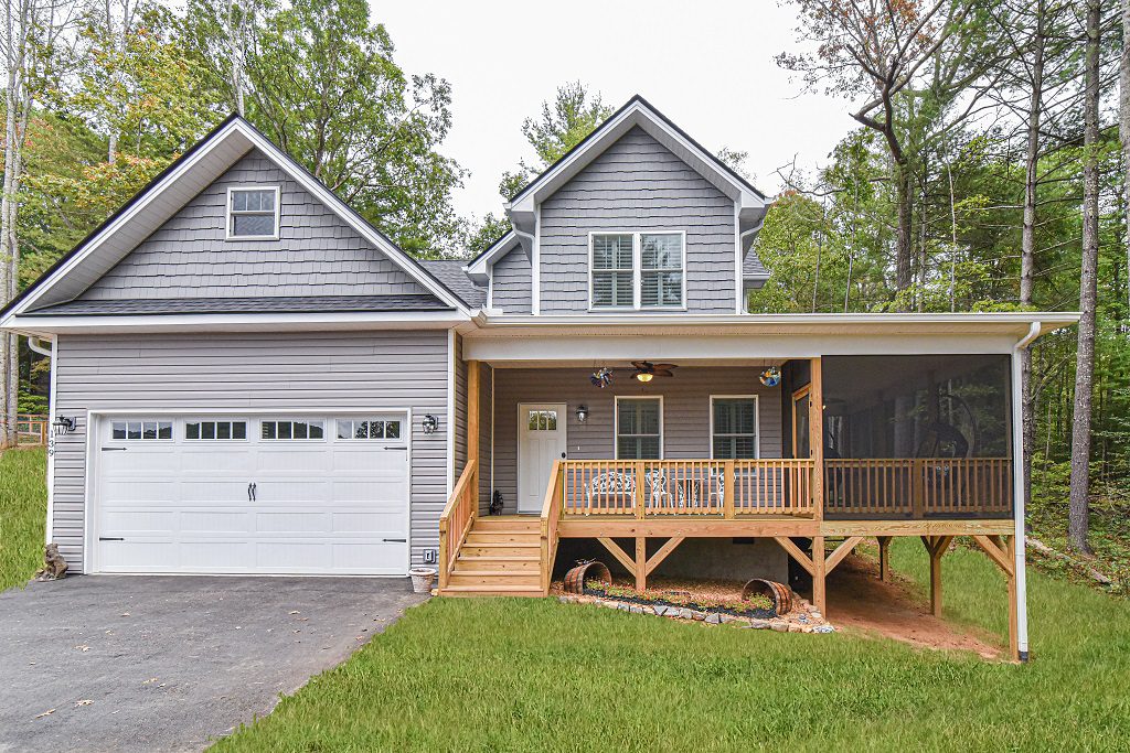 Gray two-story home with a two-car garage, screened porch and wood deck stairs