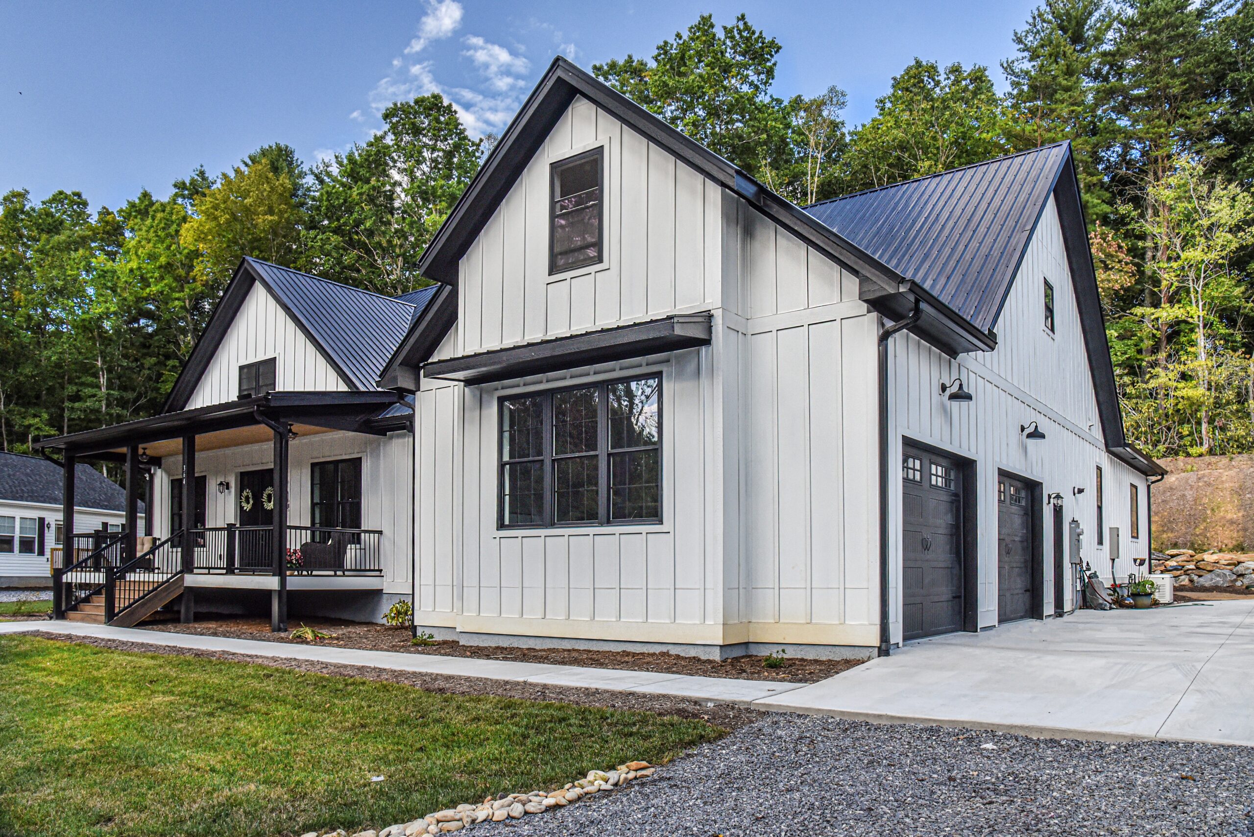 Front elevation of the white farmhouse with black windows and a covered porch