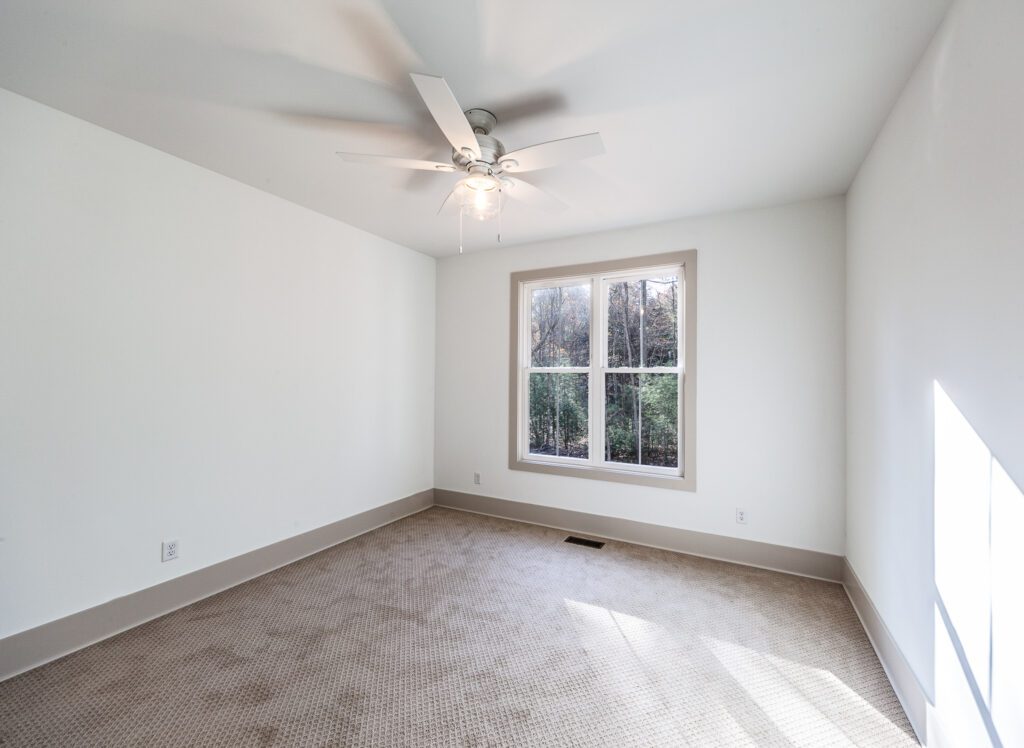 Bedroom with a ceiling fan, single window and neutral carpet