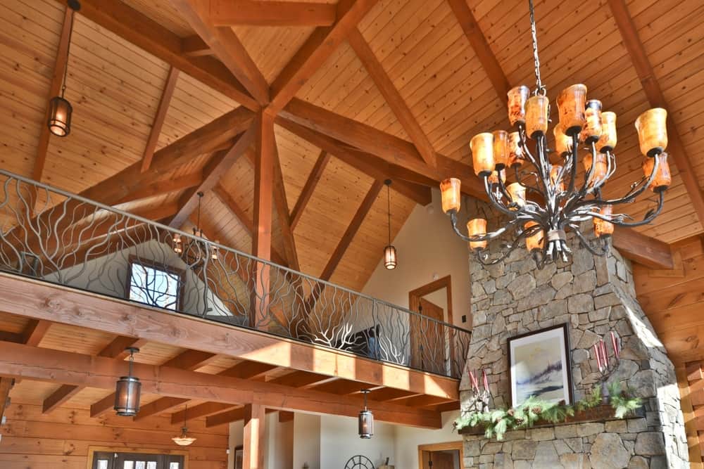 Timber-framed loft with exposed trusses, an antler-style chandelier and a metal railing