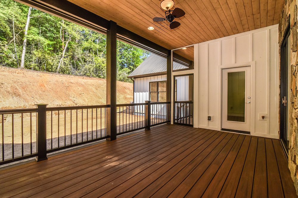 Covered back porch with a stained wood ceiling, ceiling fan and stone accents