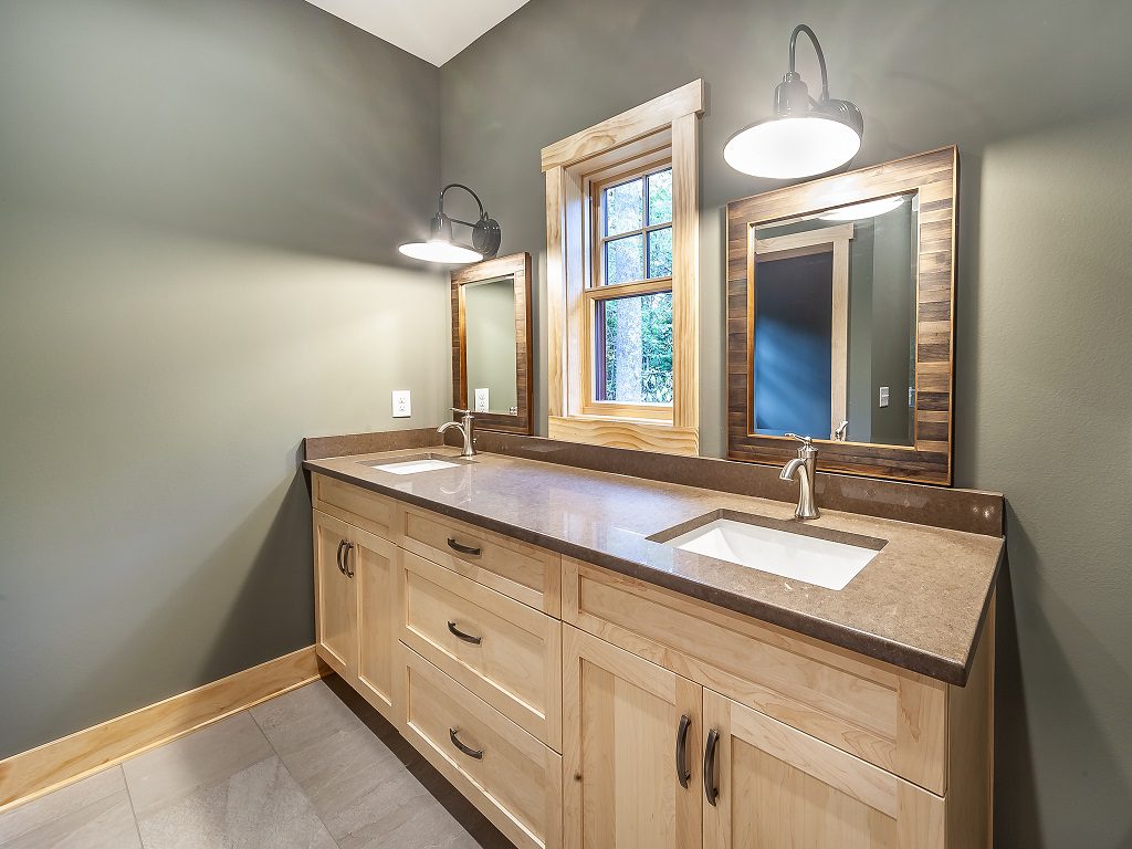 Primary bath with a double vanity, wood cabinets and mirrors framed in reclaimed wood
