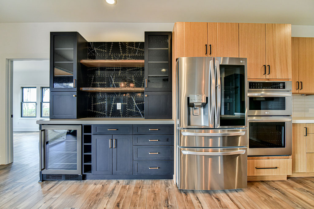 Wet bar wall with navy cabinets, glass uppers, wine storage and a built-in refrigerator