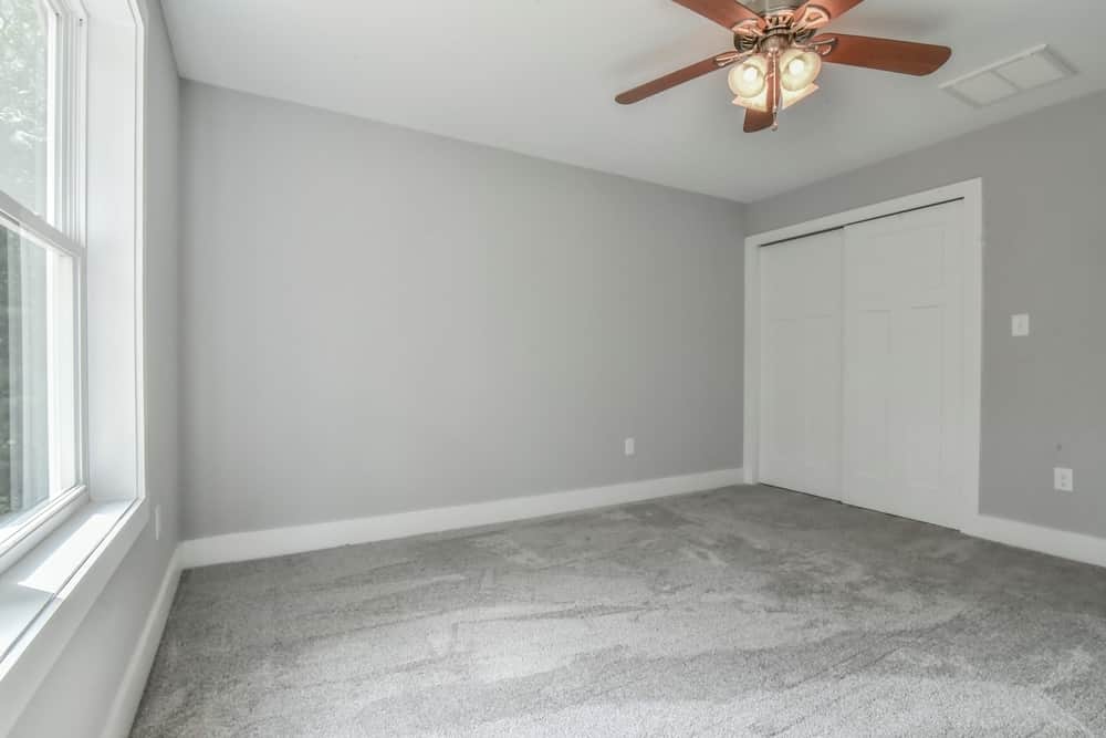 Carpeted bedroom with a closet, ceiling fan and windows