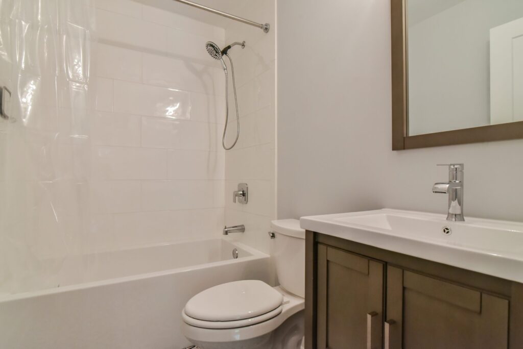 Guest bath with a tub and shower surround, a wood vanity and a framed mirror