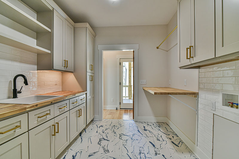 Butler's pantry and laundry area with cream cabinets, a marble-look floor and a built-in counter
