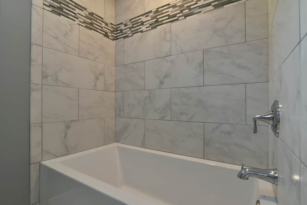 Guest bath with a marble-look tiled tub surround and a glass mosaic accent band