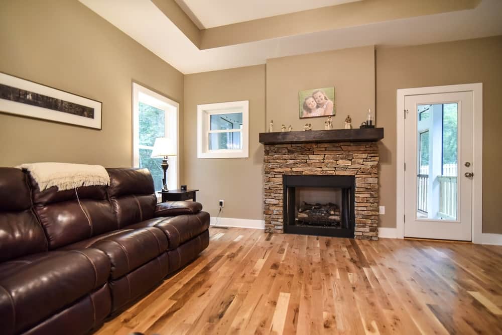 Living room with a stone fireplace, hickory floors and leather seating