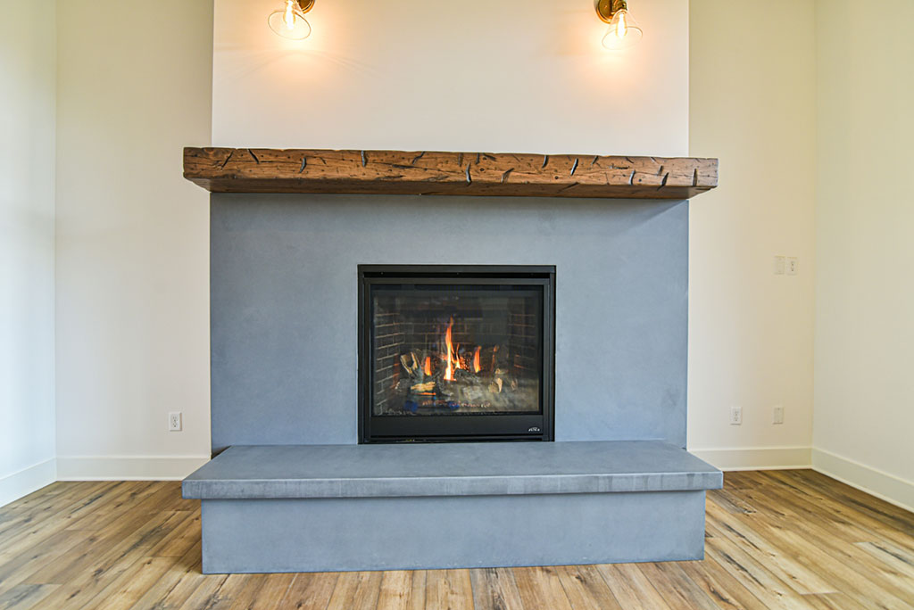 Gas fireplace with a concrete surround and hearth and a reclaimed wood mantel