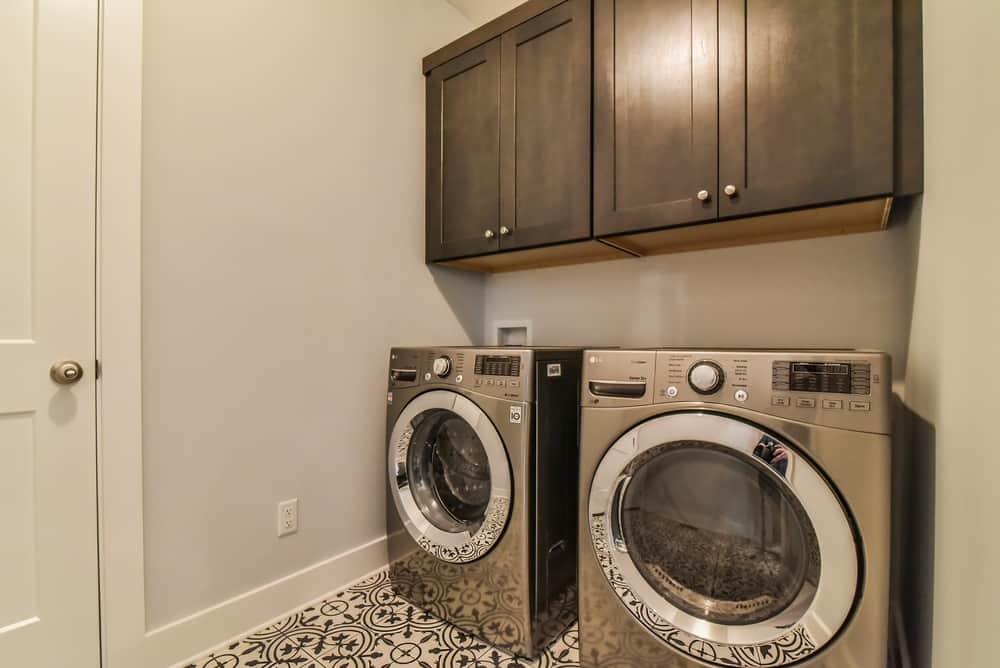 Laundry room with dark upper cabinets, a patterned tile floor and a washer and dryer