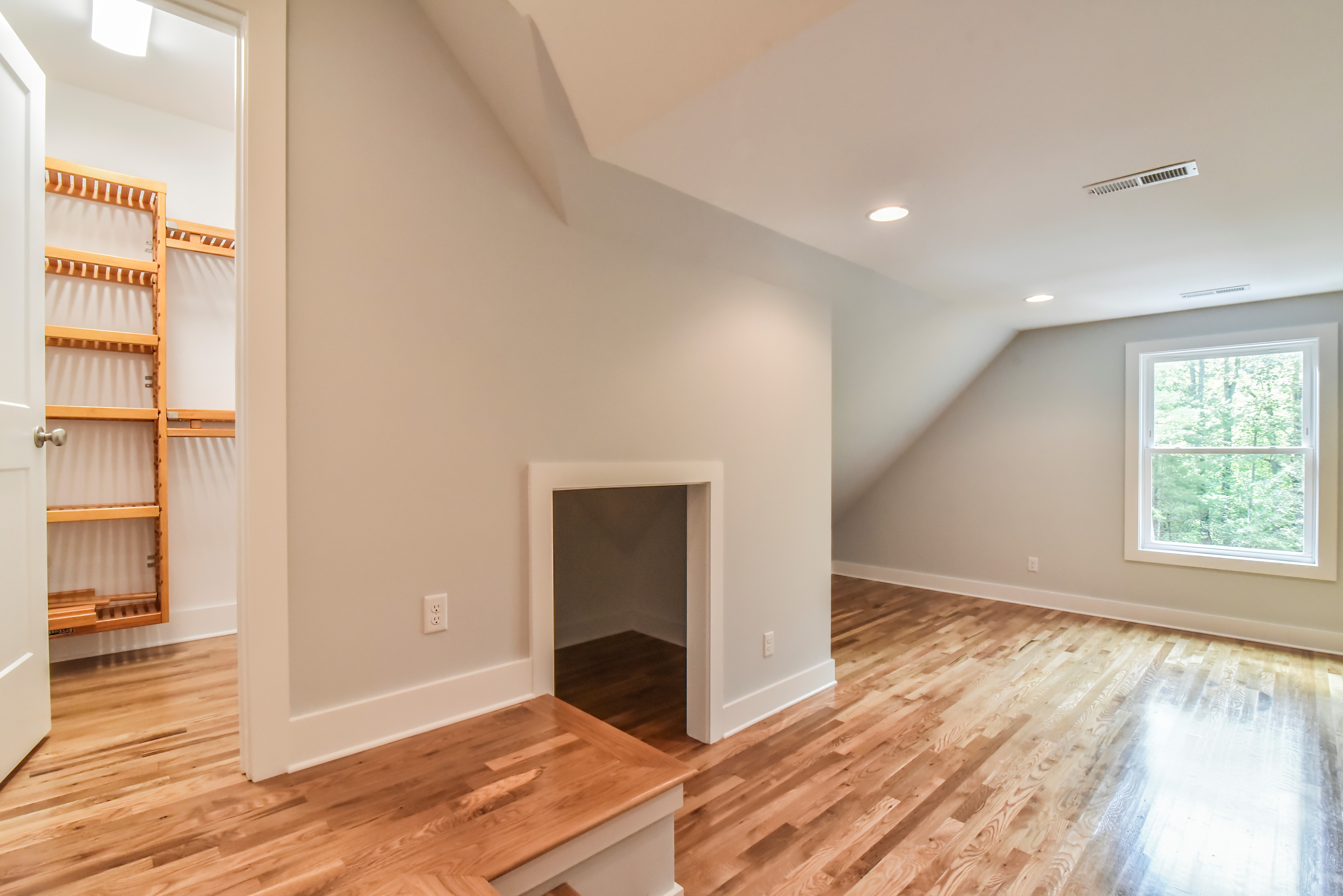 Upstairs room with open shelving, a sloped ceiling and hardwood floors