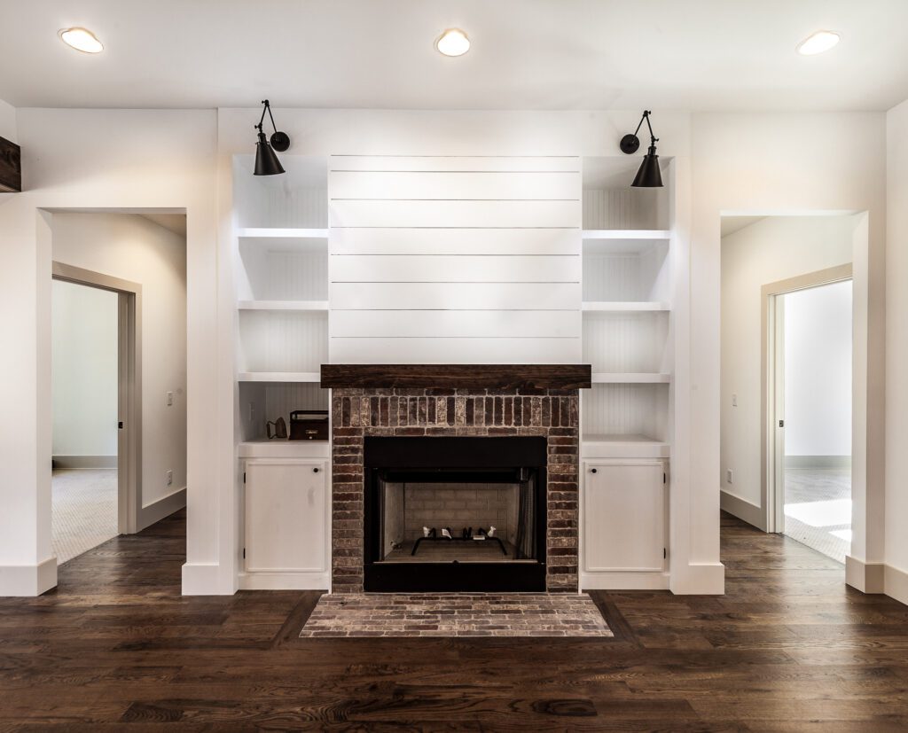 Brick fireplace with a shiplap surround and flanking white built-in shelves