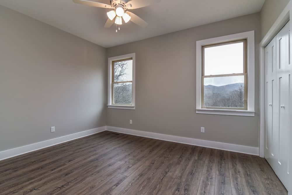 Bedroom with two windows, a closet and gray wood-look floors