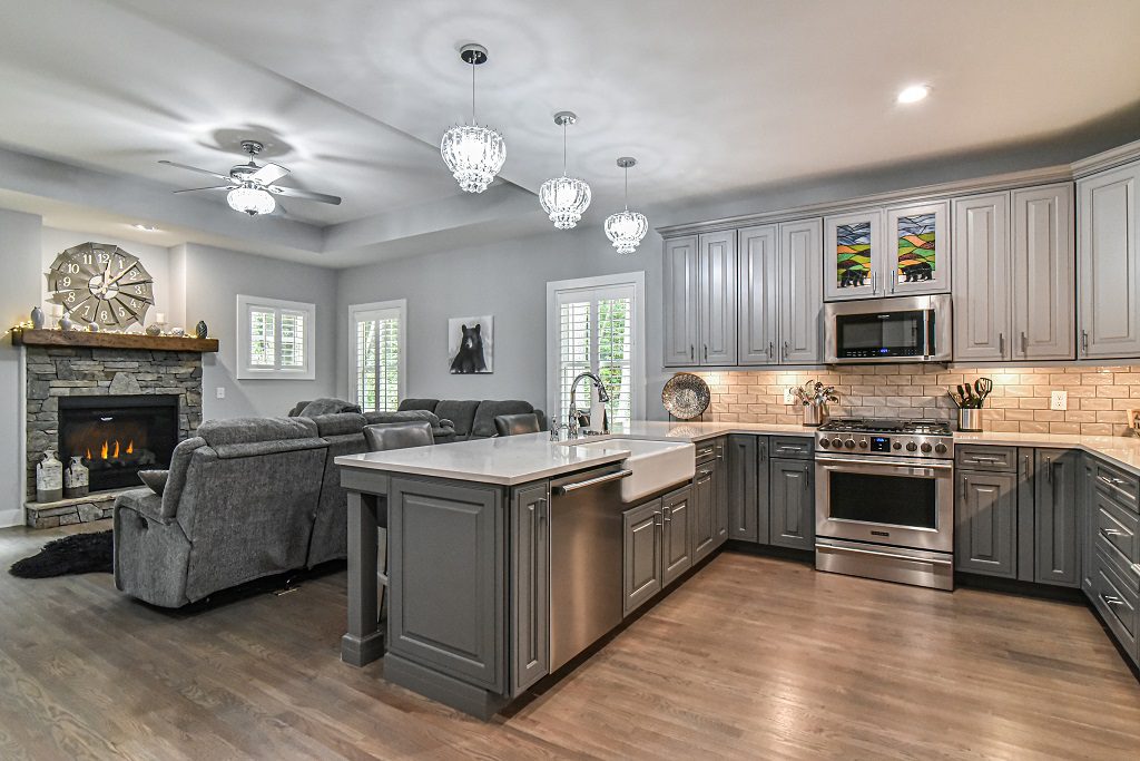 Open kitchen and living room with a stone fireplace, gray island and pendant lights