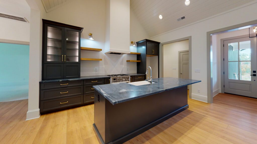 Kitchen with dark cabinets, a large island, vaulted ceiling and light wood floors
