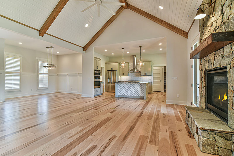 Open living area with a vaulted beamed ceiling looking toward the kitchen and stone fireplace