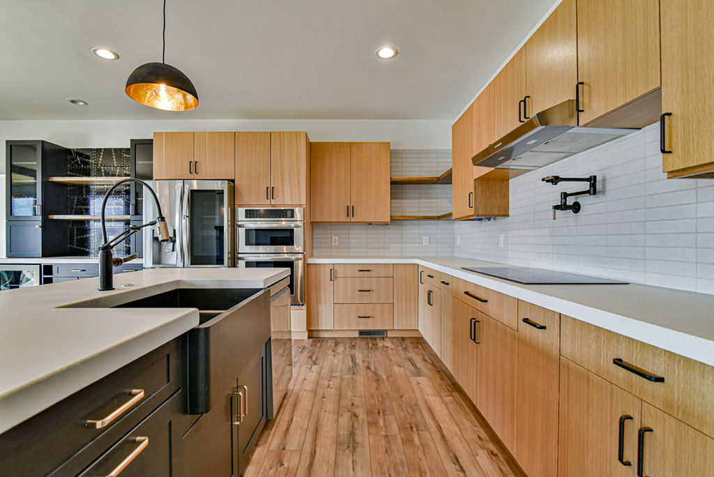 Kitchen with light wood cabinets, quartz counters, a dark island and stainless appliances