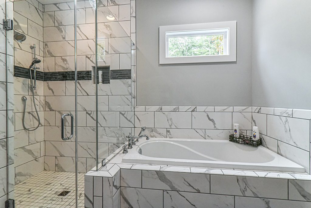Primary bath with a marble-tiled corner tub and a glass walk-in shower