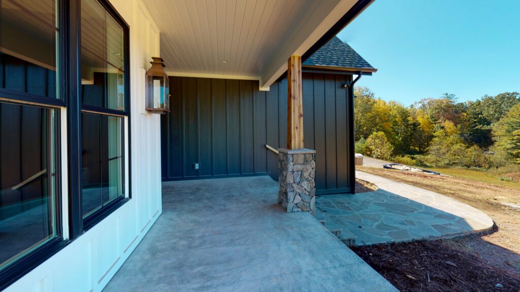 Covered patio with stone columns and dark siding looking out to the mountains